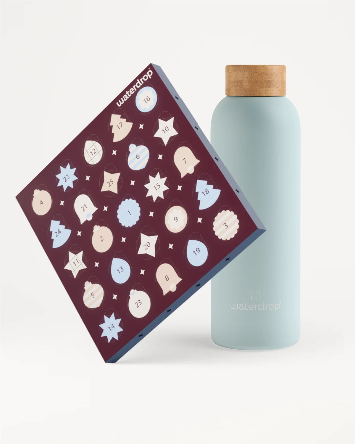 Bouteille réutilisable bleu clair avec bouchon en bois à côté d’un calendrier de l’Avent violet décoré de flocons de neige blancs et bleus.