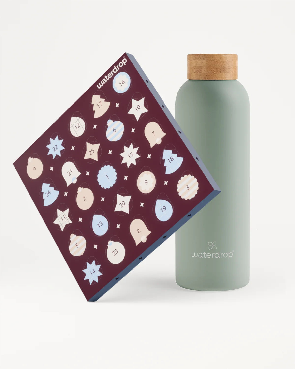 Boîte violette foncé inclinée avec de multiples icônes circulaires claires à côté d'une bouteille vert pâle avec bouchon en bois.