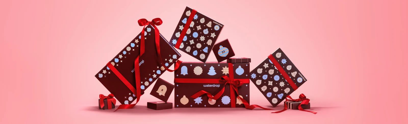 Boîtes cadeau disposées en grande composition sur un fond rose dégradé.