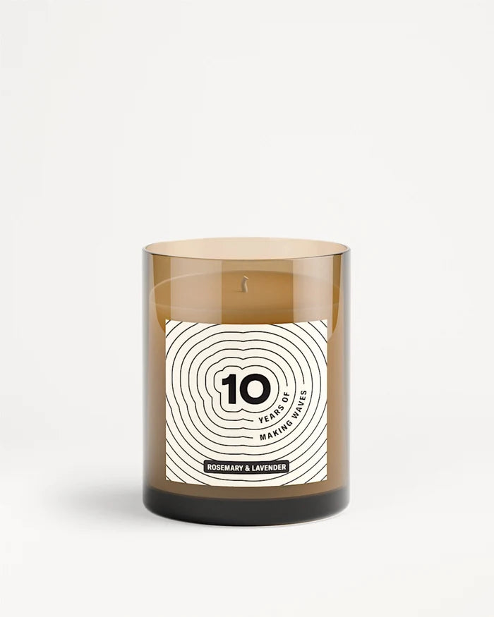 Bougie dans un bocal en verre brun avec étiquette blanche et motif de cercles concentriques.